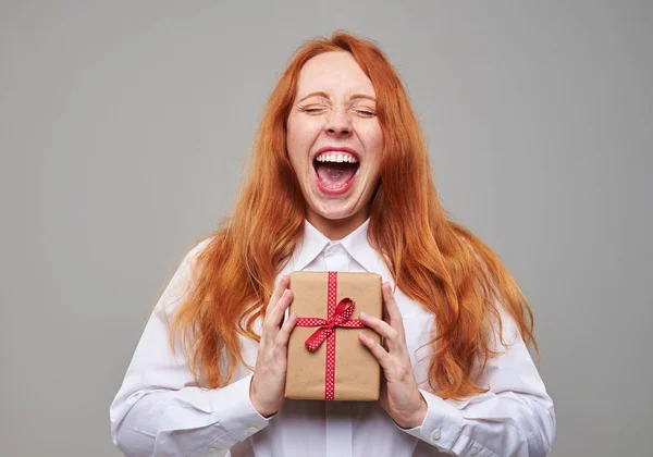 Gioiosa ragazza dai capelli rossi con regalo chiuso in mano — Foto Stock