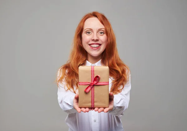 Sorrindo menina de cabelo vermelho dando caixa de presente — Fotografia de Stock