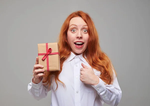 Sensitive red hair girl holding a present box isolated over back — Stock Photo, Image