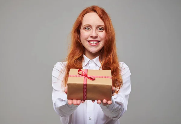 Good-looking redhead teenager offers a gift box — Stock Photo, Image