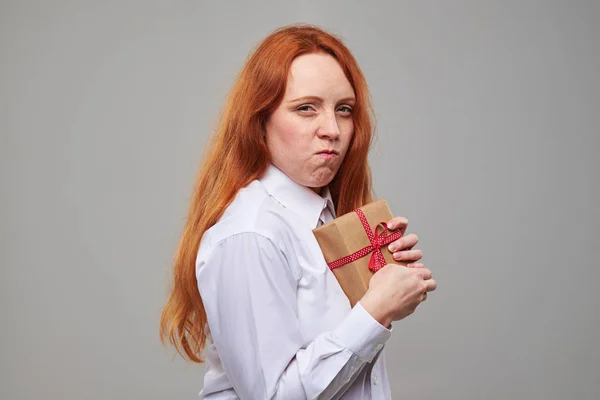 Greedy red hair teen hiding gift box with a present — Stock Photo, Image