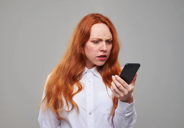 Chica desconcertada mirando la pantalla del teléfono —  Fotos de Stock