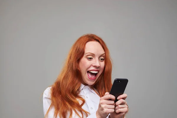 Chica alegre pelo rojo usando el teléfono móvil —  Fotos de Stock