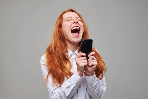 Веселая девушка смеется, пользуясь телефоном — стоковое фото