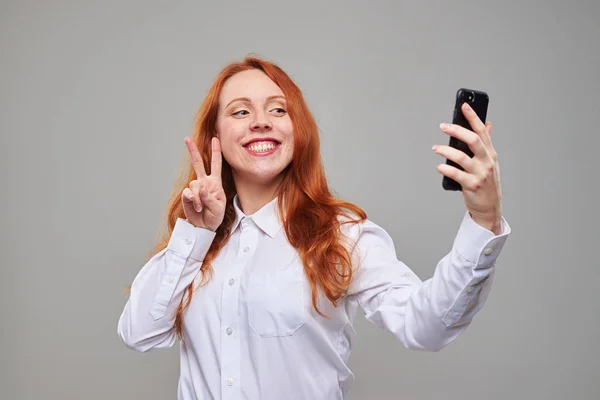 Cheerful girl holding peace sing while posing at the camera — Stock Photo, Image