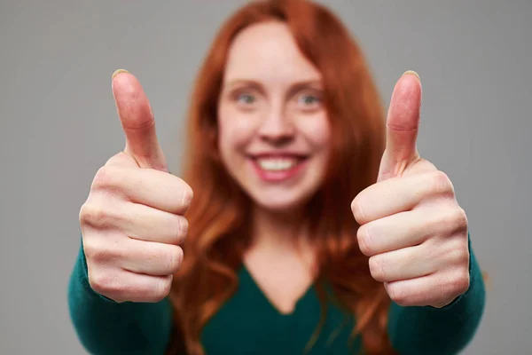 Rack fokus på tummen upp ges av kvinna med rödbrunt hår — Stockfoto