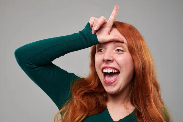 Young woman with loser sign on forehead — Stock Photo, Image