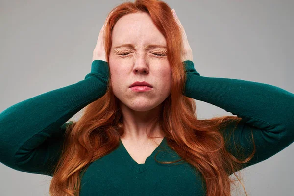 Flicka med rött hår som täcker öronen med händer — Stockfoto