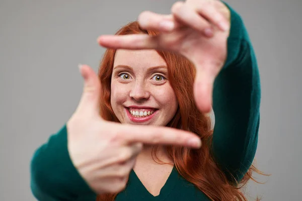 Mulher positiva com cabelo de auburn fazendo uma moldura com os dedos — Fotografia de Stock