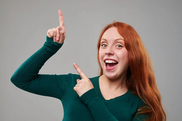 Mujer joven y feliz señalando hacia arriba a un espacio de copia — Foto de Stock