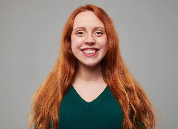 Softly smiling young woman with red hair posing at the camera — Stock Photo, Image