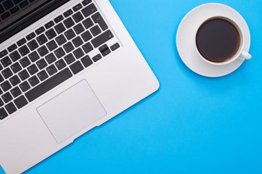 Bir fincan kahve ile açık bir laptop atış üzerinde mavi fl kırpılmış