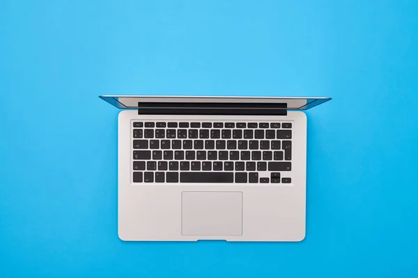 Laptop prata aberto deitado no flatlay azul — Fotografia de Stock