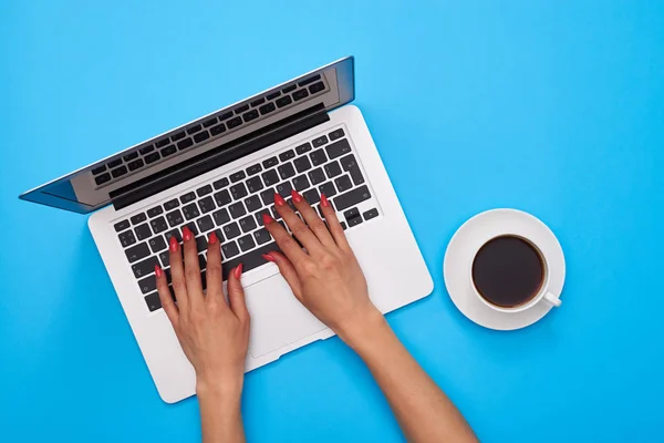 Mãos de mulher em um teclado do computador portátil moderno sobre o apartamento azul — Fotografia de Stock