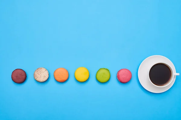 Stretch of macaroons with a cup of coffee in the end with a copy — Stock Photo, Image