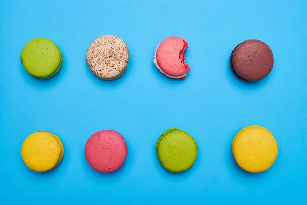 Macaron morso sdraiato tra gli altri su un piatto blu — Foto Stock