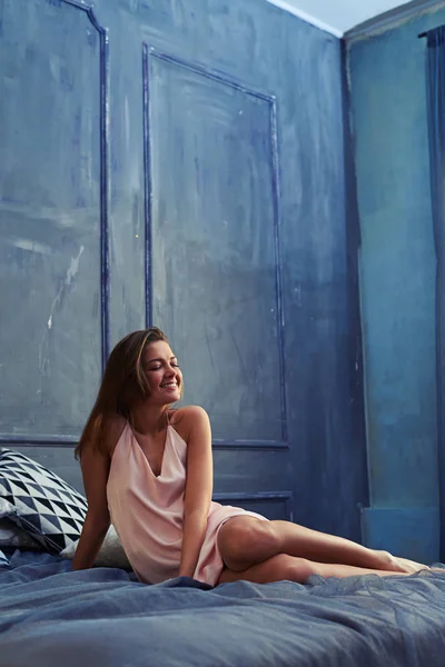 Elégedett, fiatal nő ült az ágy az alvás után — Stock Fotó