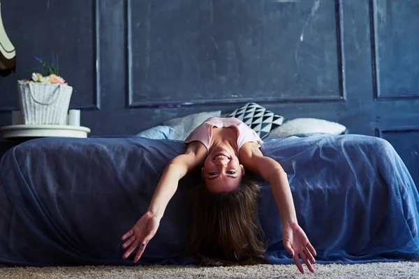 Забавная молодая женщина с распростертыми руками, лежащая на кровати — стоковое фото