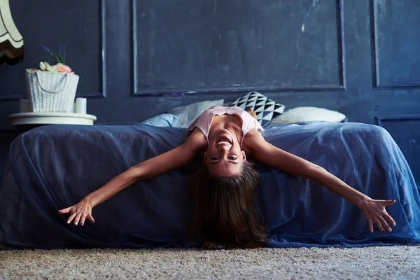 Menina feliz espalha braços ao longo da cama pela manhã — Fotografia de Stock