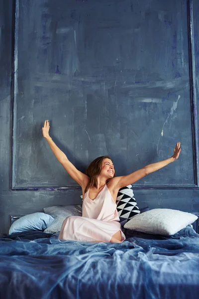 Cheerful girl stretching in bed while looking at the window — Stock Photo, Image