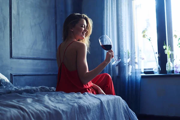 Pozitivní elegantní dívka v červeném hedvábí celkové, ochutnávka vín v se — Stock fotografie