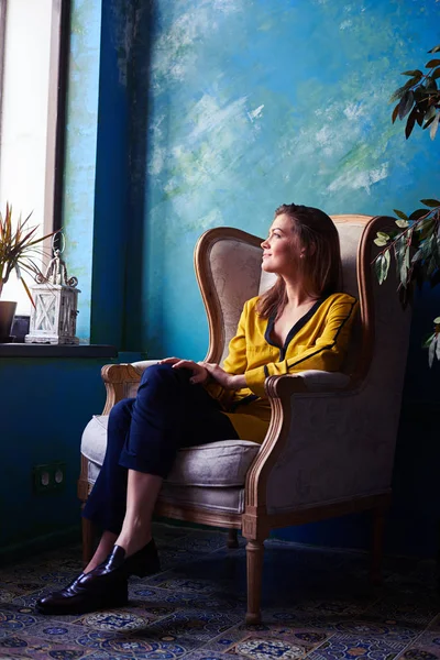 Chica inspirada sentada en un sillón delante de la ventana y — Foto de Stock