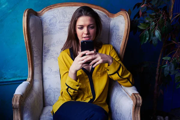 Chica intencional mirando atentamente la pantalla de un teléfono inteligente —  Fotos de Stock