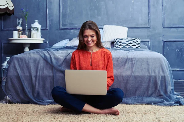 Zadowoleni, młoda dziewczyna, siedząc w siadzie skrzyżnym i pracę na laptopie — Zdjęcie stockowe