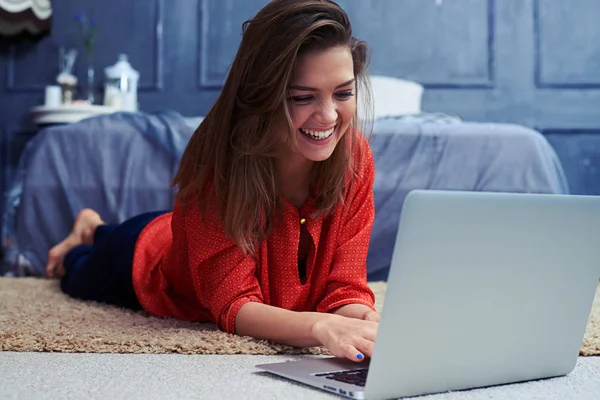 Vicces lány beszélget a laptop mellett a földön fekve — Stock Fotó