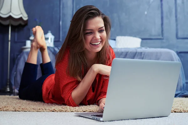 Sorrindo menina deitada no chão na frente do laptop — Fotografia de Stock