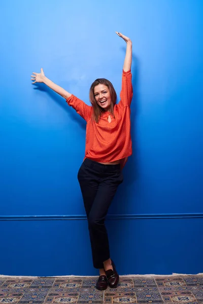 Joyful fêmea na roupa da moda com os braços levantados posando no st — Fotografia de Stock