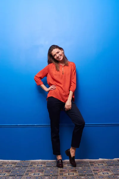 Sonriente chica posando sobre puntillas aisladas sobre fondo azul — Foto de Stock