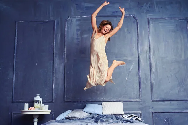 Young excited woman jumping on bed — Stock Photo, Image