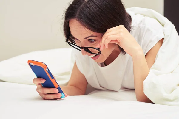 Здивована жінка тримає окуляри, читаючи щось на t — стокове фото