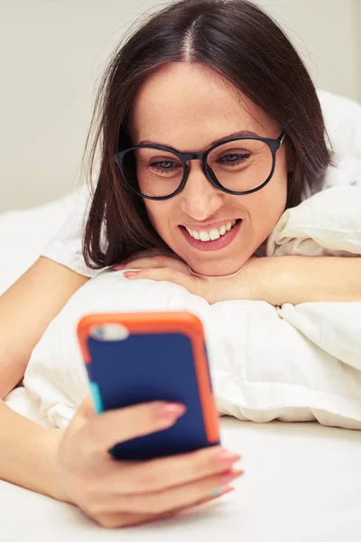 Female wearing glasses reading message on her mobile phone with