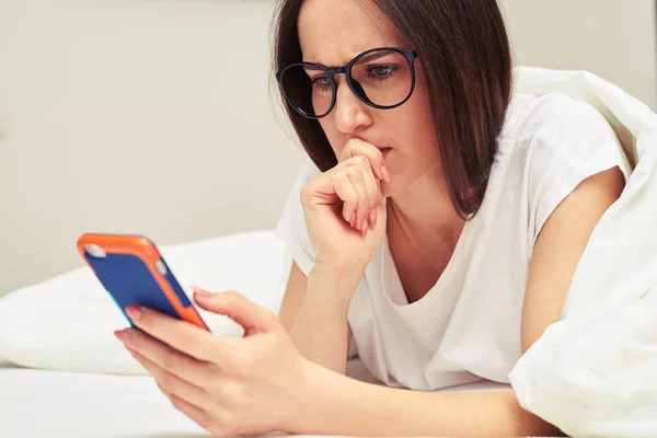 Upptagen kvinna tittar på telefon liggande på b — Stockfoto