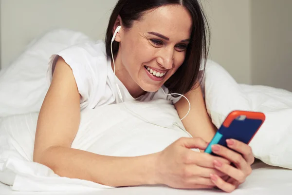 Mujer sonriente se comunica con alguien a través de un teléfono inteligente —  Fotos de Stock