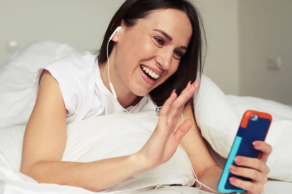 Woman communicates with someone via smartphone while lying on th