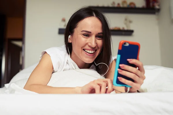 Sonriente morena mirando la pantalla del teléfono mientras ly —  Fotos de Stock