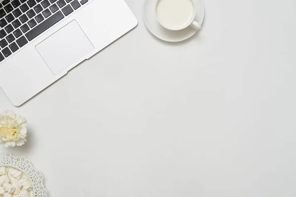 Desktop con computer portatile, tazza di latte e fiore bianco, piatto posare pict — Foto Stock