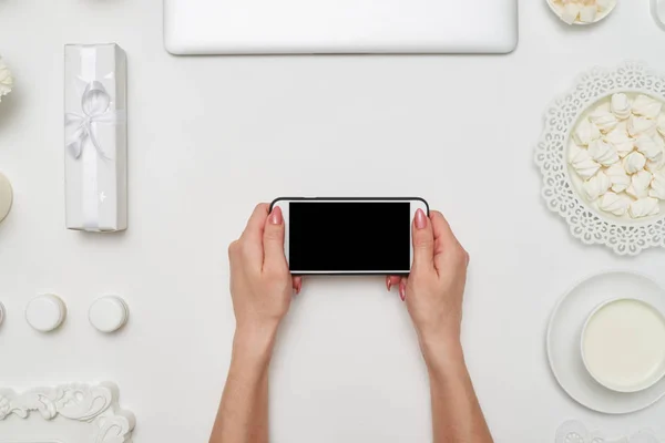 Vrouwtje houden horizontaal cellphone, plat lag — Stockfoto