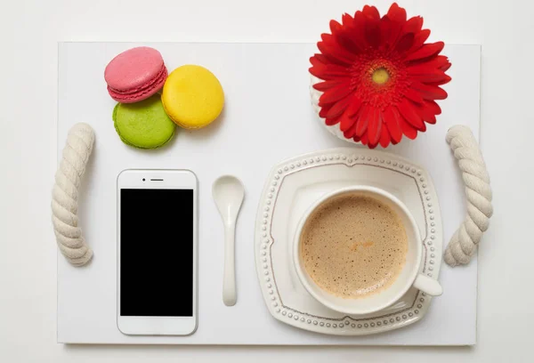 Ontbijt met koffie, bitterkoekjes en mobiele telefoon op dienblad — Stockfoto