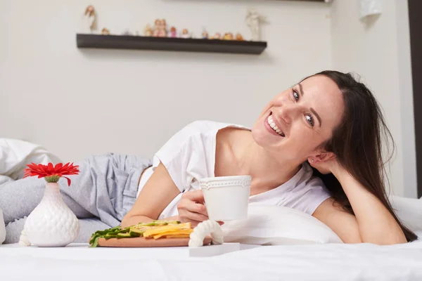 Femme apprécie le petit déjeuner romantique tout en se relaxant au lit — Photo