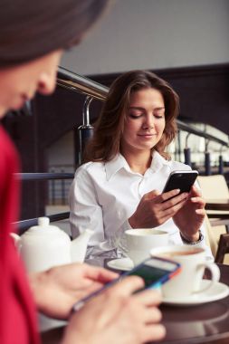 İki güzel konsantre kadın elbiseli smartphones içinde çalışma 