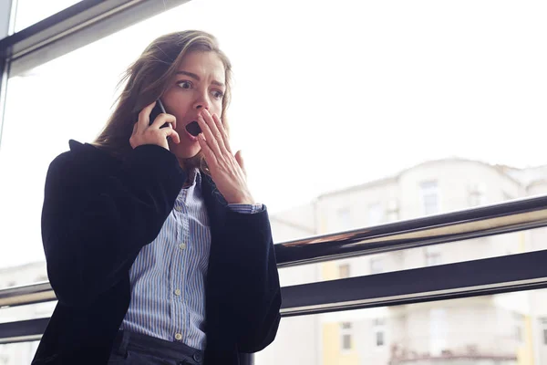 Choqué femme d'affaires couvrant la bouche avec la main pendant la conférence téléphonique — Photo