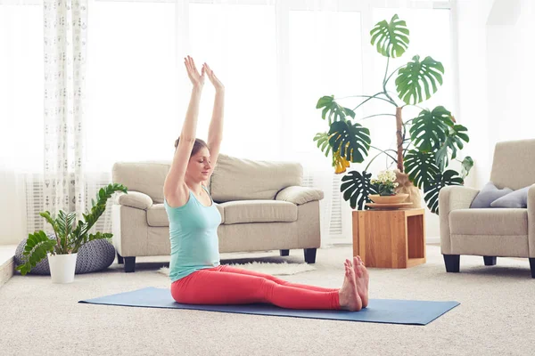 Тощая женщина сидит на коврике для йоги и практикует йогу — стоковое фото