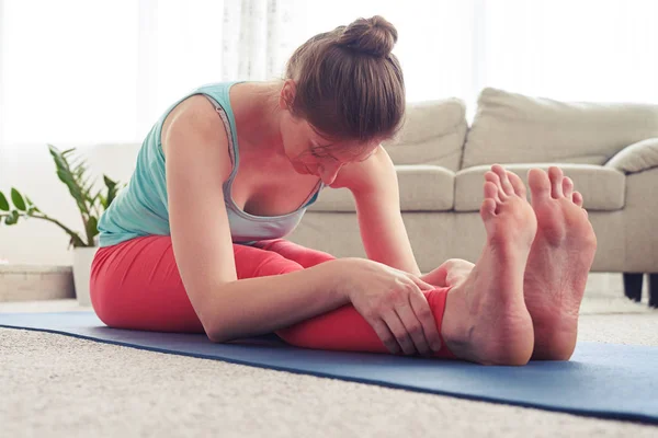 Gut aussehende Frau dehnt sich in sitzender Vorwärtsbeugeposition — Stockfoto