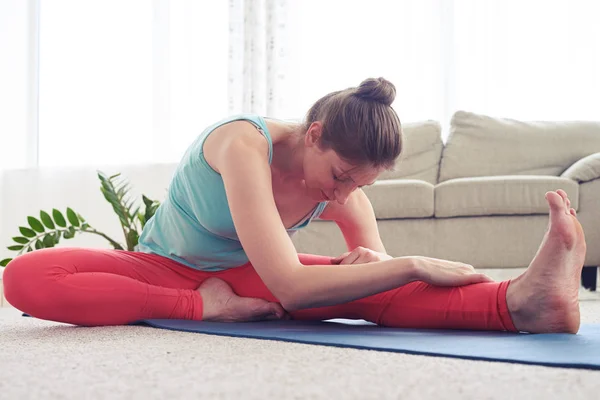 Mujer relajada practicando yoga en pose de yoga cabeza a rodilla —  Fotos de Stock