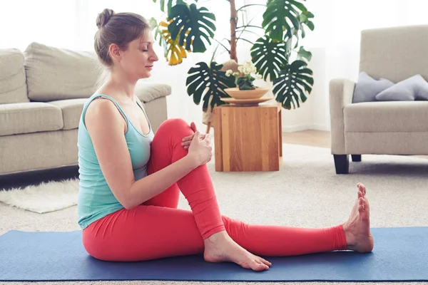 Linda fêmea meditando e amadurecendo músculos no tapete de ioga — Fotografia de Stock