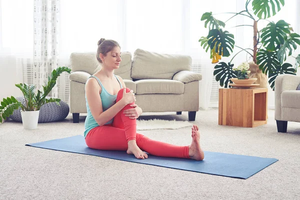 Chica guapa haciendo pose de yoga en colchoneta de yoga interior — Foto de Stock